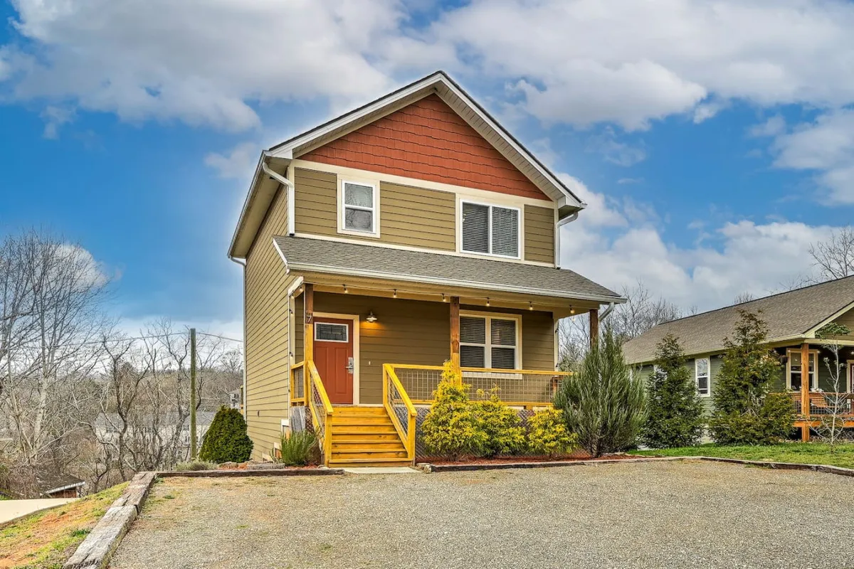 The image captures the inviting exterior of the home, featuring a front porch with a staircase, surrounded by a landscaped garden. The setting is warm and welcoming, suggesting a place where families can gather outdoors, enjoy meals on the porch, or relax after a day of adventure. The porch offers views of the sunset and hints at tranquil mornings.