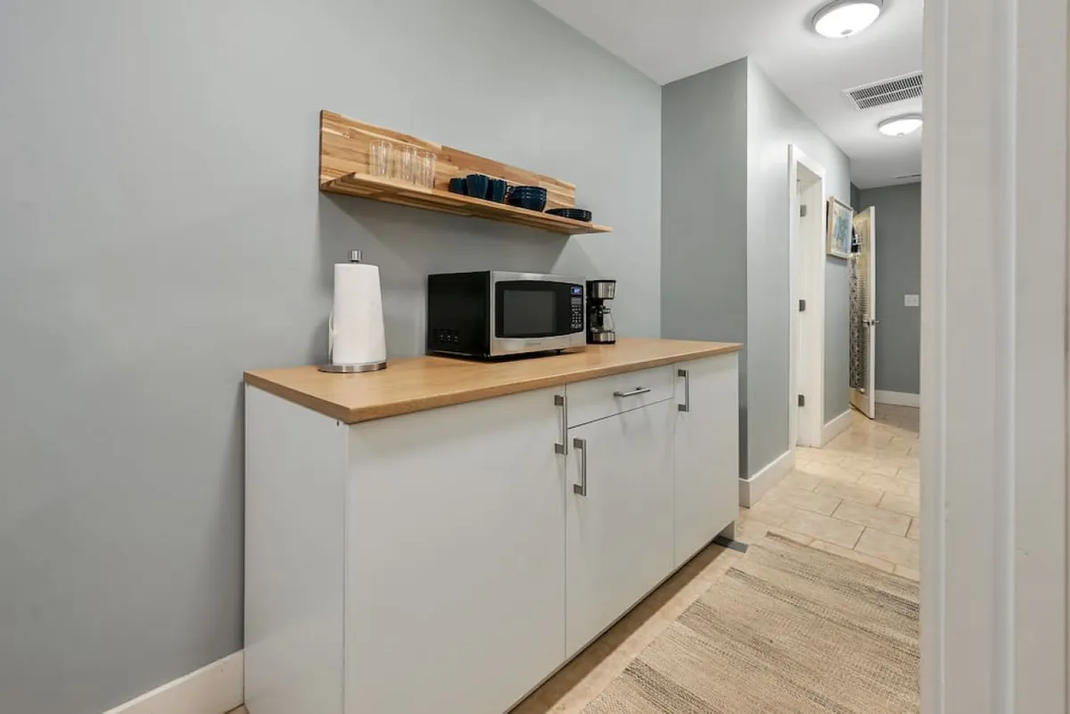 A functional kitchen nook equipped with a microwave, coffee maker, and a shelf with dishes. The scene evokes the convenience of preparing late-night snacks or morning coffee after a night out on the town.